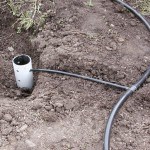 A short section of drain pipe is used to create an outlet shield. Note: to finish the system basin is filled with mulch and tubing buried. 